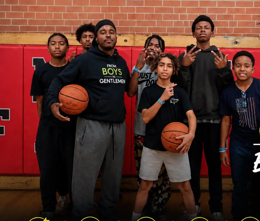 A From Boys to Gentlemen mentor and students holding basketballs in the Mann STEAM Academy gym.